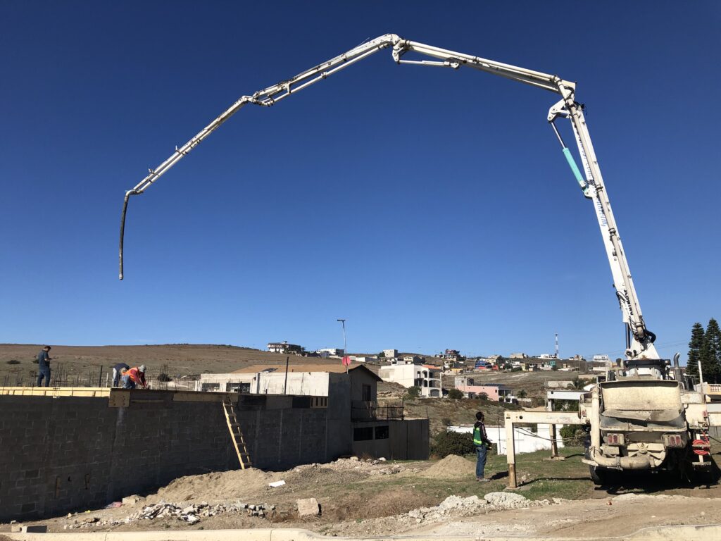 Colado de losa en segundo piso con camión y manguera de bombeo de concreto, representando etapa de construcción estructural.